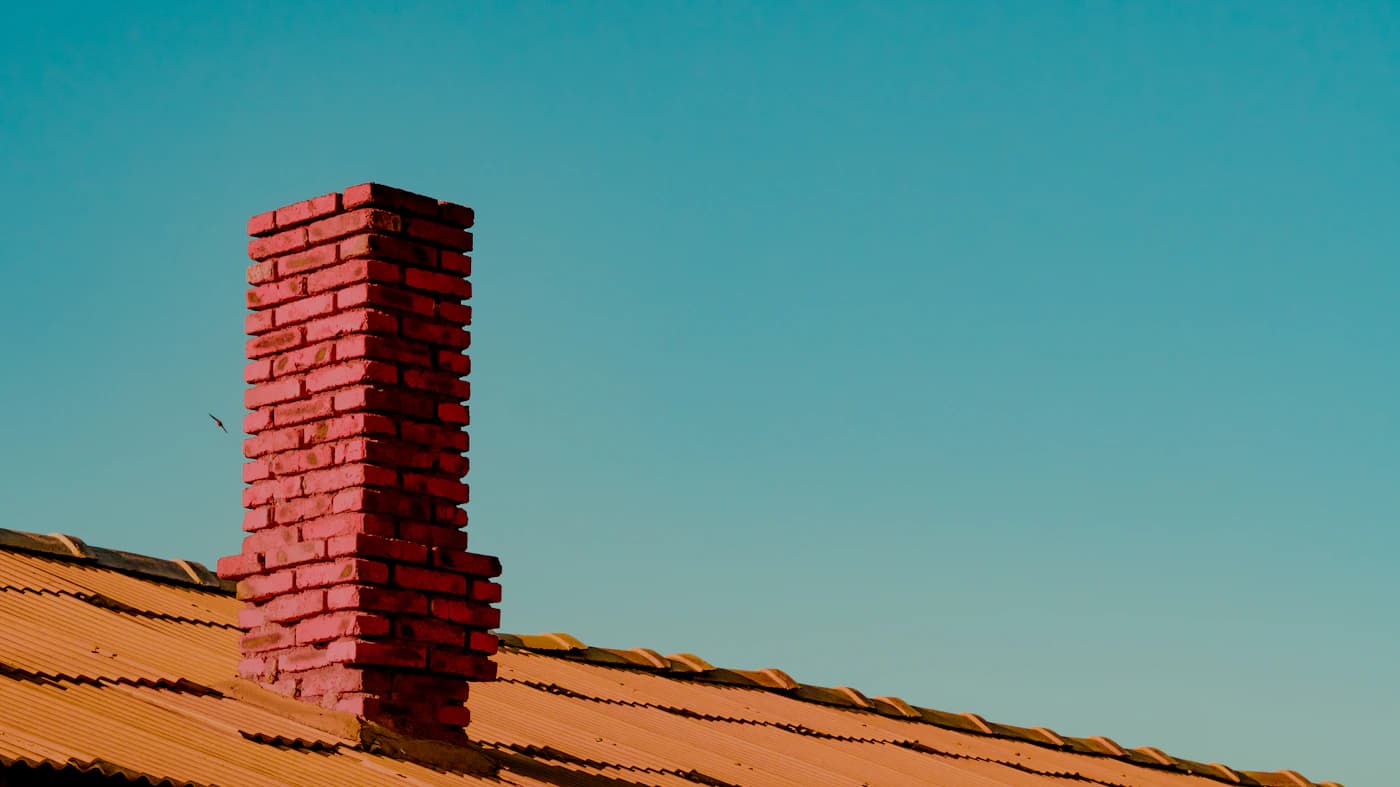 Brick chimney projecting through an orange tiled roof
