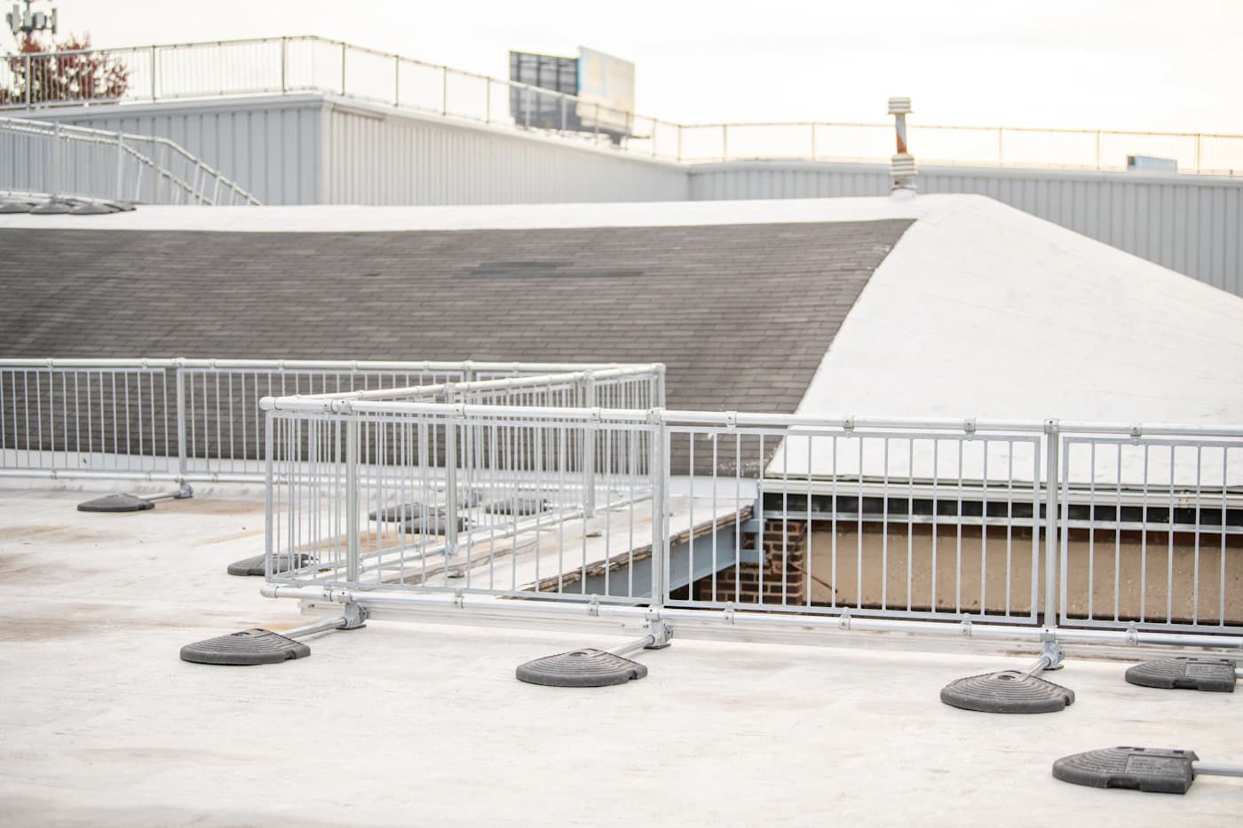 Low-slope rooftop with guardrails around an opening and adjacent roof sections