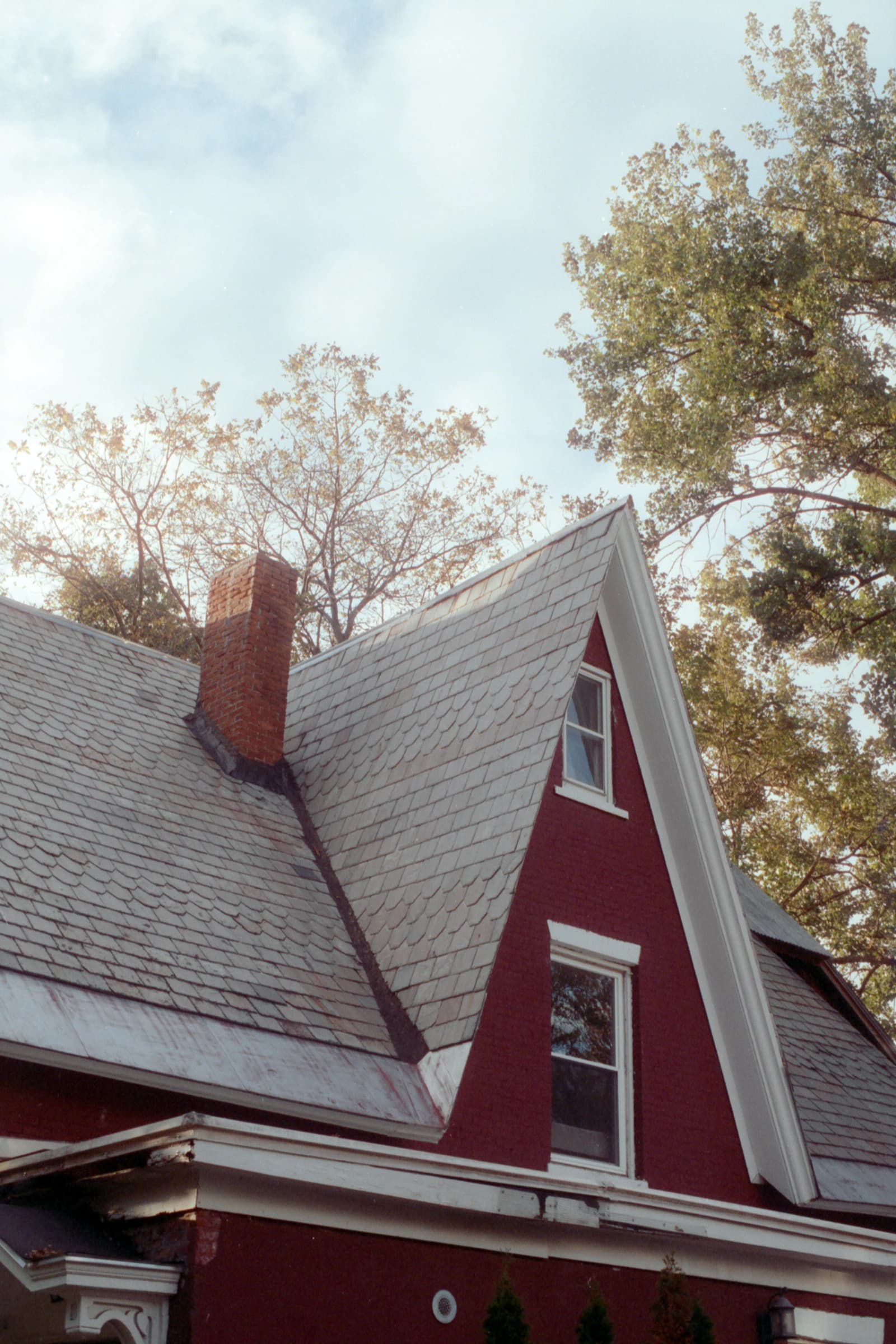 Red house with a pitched shingle roof and brick chimney